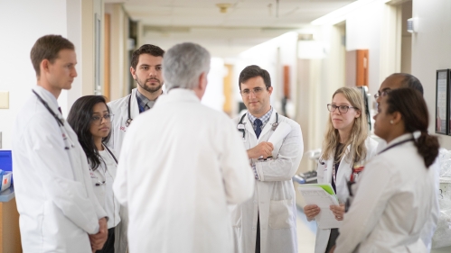 A professor speaks with medical students during rounds