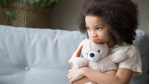 A little girl hugs a teddy bear