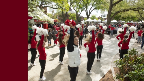 Rutgers cheerleaders raising red and white pompoms and cheering at Rutgers Day