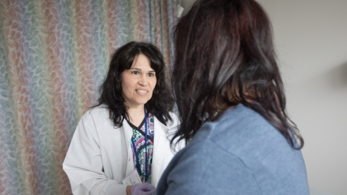 A nurse takes vitals from a patient in an exam room