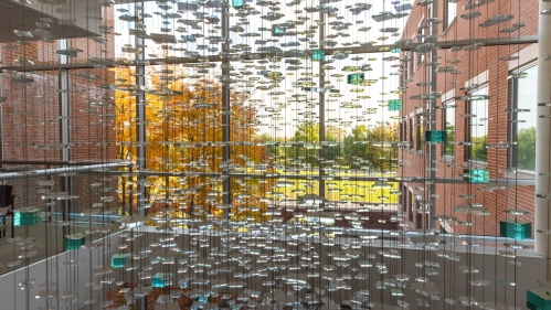 A sculpture of glass tiles hangs in the atrium of the school of public health 