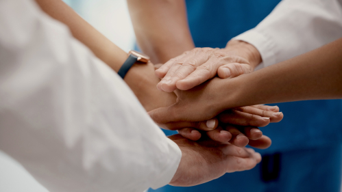 Doctors stack their hands in a circle to show support for one another