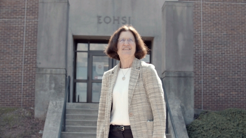 Professor Iris Udasin stands in front of the EOHSI building on a sunny day