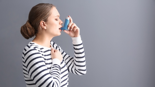 A woman uses an inhaler for asthma.
