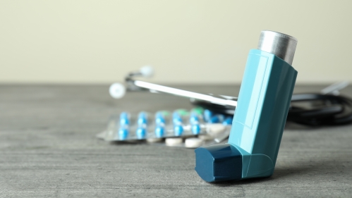 Asthma medication and an inhaler sit on a table next to a stethoscope.