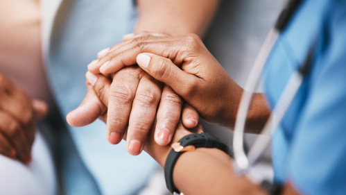 A healthcare worker holds a patient’s hand