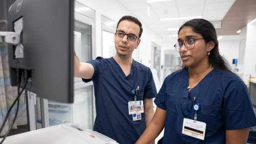 Residents look at a computer monitor in the hospital.