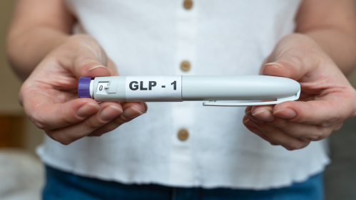 Women in white shirt holding GLP-1 medication 