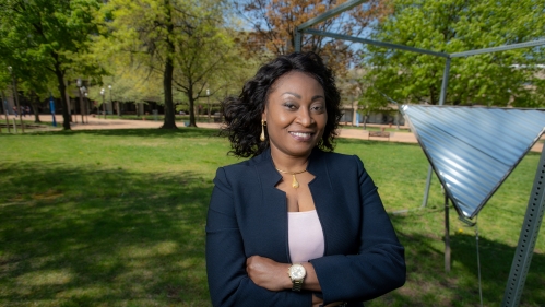 Chinwe Mercy Izegbu standing with her arms folded outside on campus