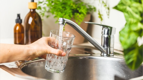 Person filling glass with water from a faucet