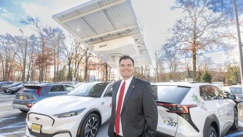 William O’Brien, assistant vice president of IP&O with two of the 24 new electric vehicles purchased this fall as part of a decadelong plan to phase out all 700 of Rutgers' gas-powered vehicles. Rutgers also purchased its first two solar-powered Beam ARC charging stations this fall. This one is located at 33 Knightsbridge in Piscataway.