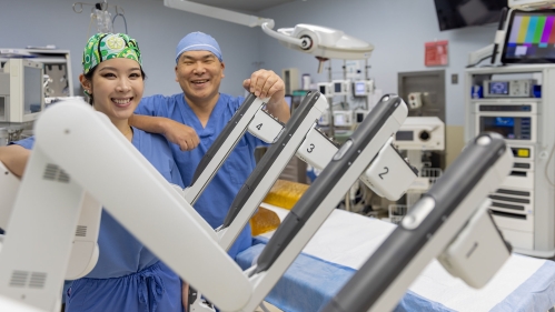 surgeons pose with surgical robot