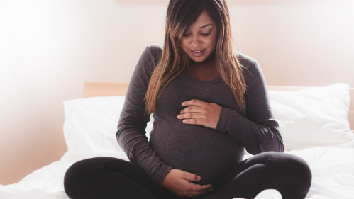 Pregnant Black Woman Sitting on Bed