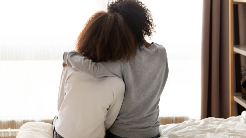 mother hugs daughter on bed