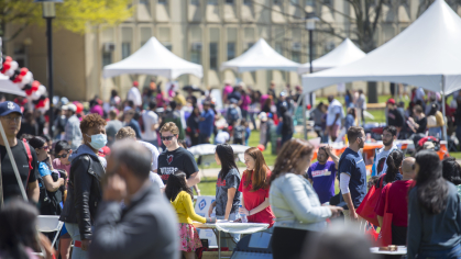 A wide shot of Busch campus as people explore booths and tents on Rutgers Day