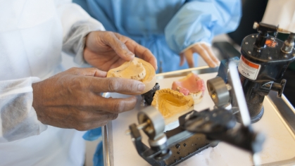 A faculty member holds a dental mold
