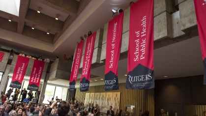 School and institute banners hang over the audience during the ceremony commemorating the Rutgers-UMDNJ integration in the main lobby of the Kessler Center on July 1, 2013.