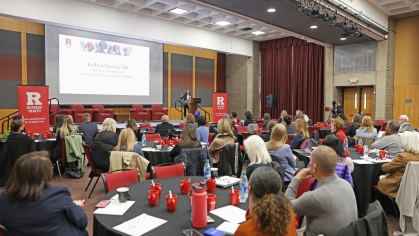 Audience members at round tables listen to a presentation during the Rutgers Health Anniversary Symposium on health equity.