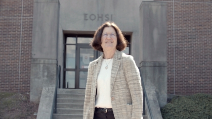 Professor Iris Udasin stands in front of the EOHSI building on a sunny day