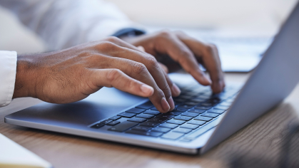 A researcher types on a laptop computer