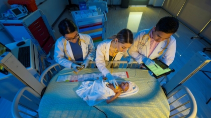 Three pharmacy students examine an infant manikin in a simulation lab