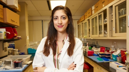 A pharmacy faculty member wearing a white coat stands in a lab