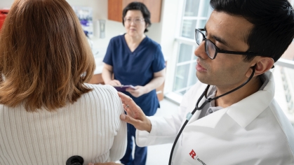 Clinicians talk and exam a patient in a clinical trial exam room