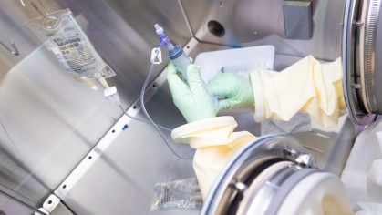A person prepares medication in a sterile chamber in the clinical research center