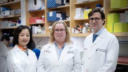 Three Rutgers Cancer Institute researchers wearing white coats standing in a lab.