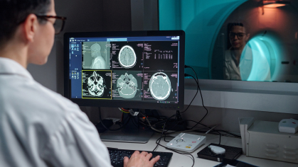 A medical technician analyzes brain scans on screen in a diagnostic lab.