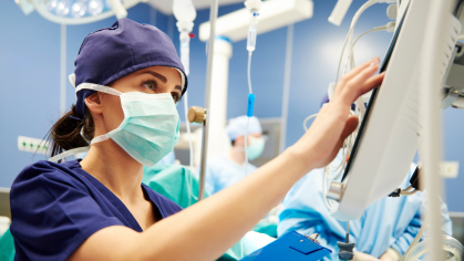 A healthcare worker adjusts a monitor in a clinical room