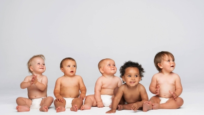Five babies in diapers seated in a row