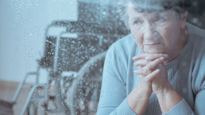 Older woman looks through rain-swept window