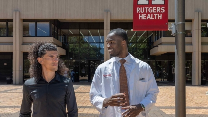 Martial arts instructor Michael Loureiro (left) and Rutgers medical student Yvan Yomba walk and talk outside of New Jersey Medical School in Newark.