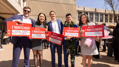 Students holding signs that say where they matched 