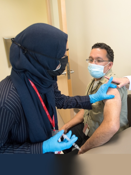 A Vax Corps member administers a covid vaccine to a Rutgers environmental services employee