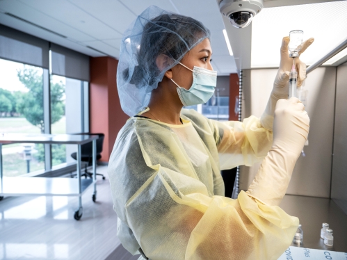 A pharmacy student prepares a medication injection