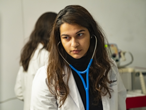 A pharmacy student uses a stethoscope in a class