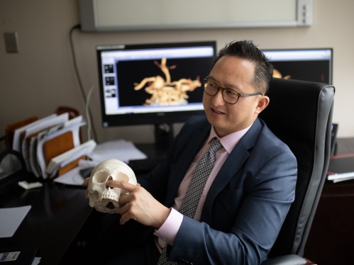 Neurosurgeon James Liu holds a replica human skull