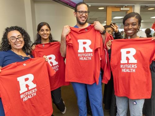 NJMS students hold up Rutgers Health shirts at an event