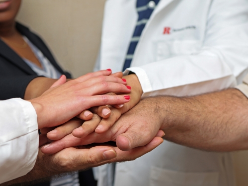 People stack their hands to signify teamwork and collaboration or community