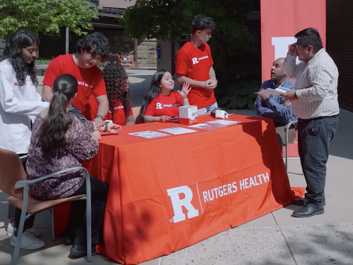 RHS Corps members sit at a table outside in New Brunswick 