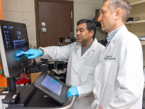 Two researchers look at an EKG screen in a lab