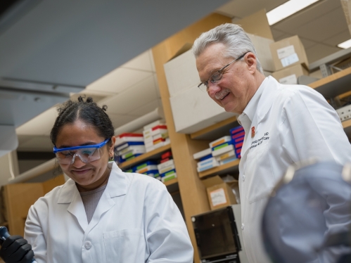 Researchers in white coats study their work in the Panettieri lab at Rutgers