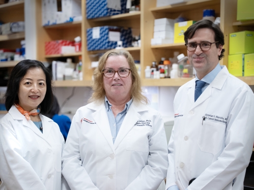 Three Rutgers Cancer Institute researchers wearing white coats standing in a lab.