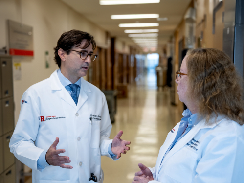 Researchers Christian Hinrichs and Eileen White talk in a hallway at Rutgers Cancer Institute.