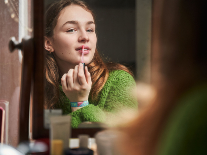 teen girl applies lip gloss