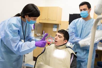 Rutgers School of Dental Medicine students examine a patient's mouth at the Delta Dental of NJ Special Care Center