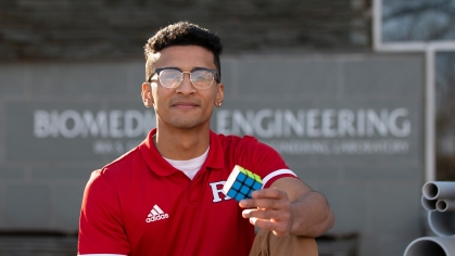 Dylan Sadiq (SOE '22) sits outside the biomedical engineering building holding a Rubik's Cube.