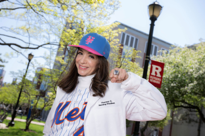 Theresa Corderi stands outside Rutgers Nursing School in Newark, dressed in a NY Mets baseball cap, jersey over a nurses white coat, flashing her Mets championship ring